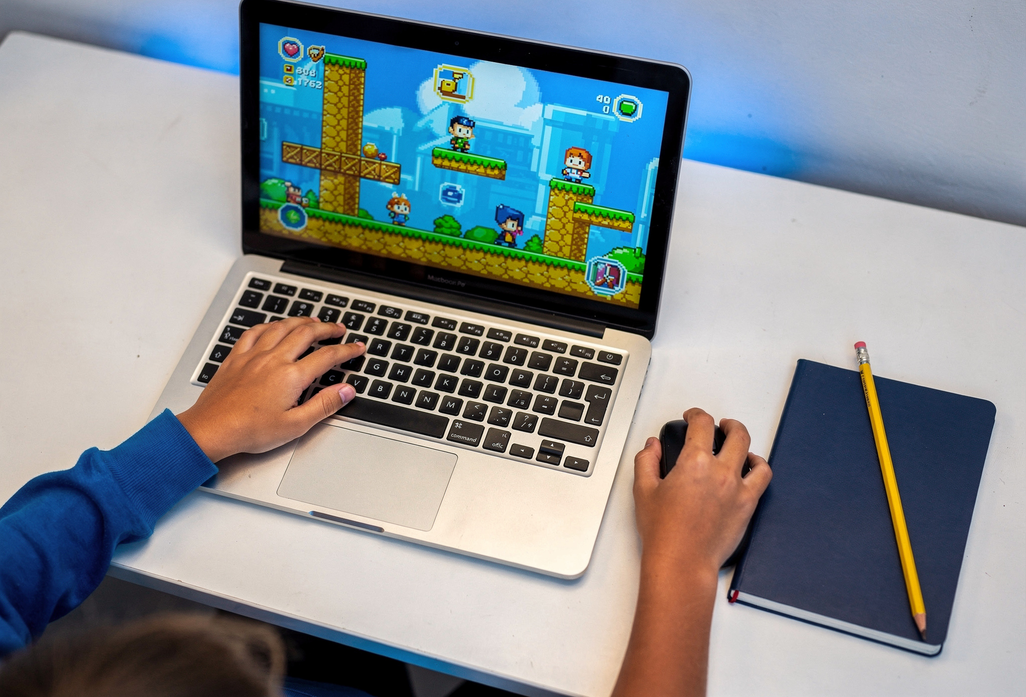 Öğrencinin oyun projesi ekranı ve kodlayan elleri laptop başında